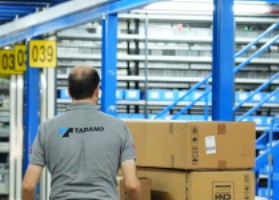 Warehouse worker moving parts boxes between storage shelves