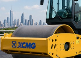 Yellow XCMG road roller with city skyline in the background