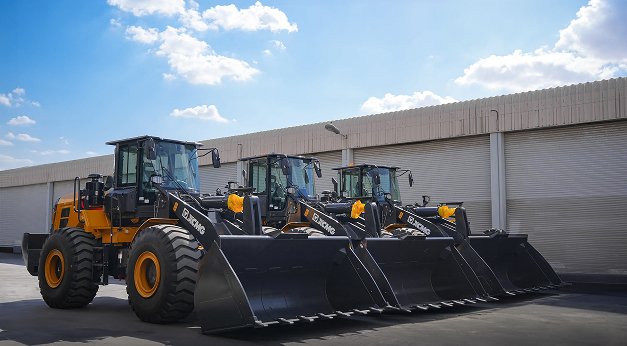 XCMG wheel loaders lined up outside a facility